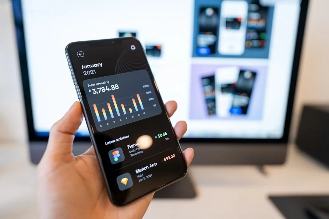 Dlon trzyma telefon z aplikacja do sledzenia finansow